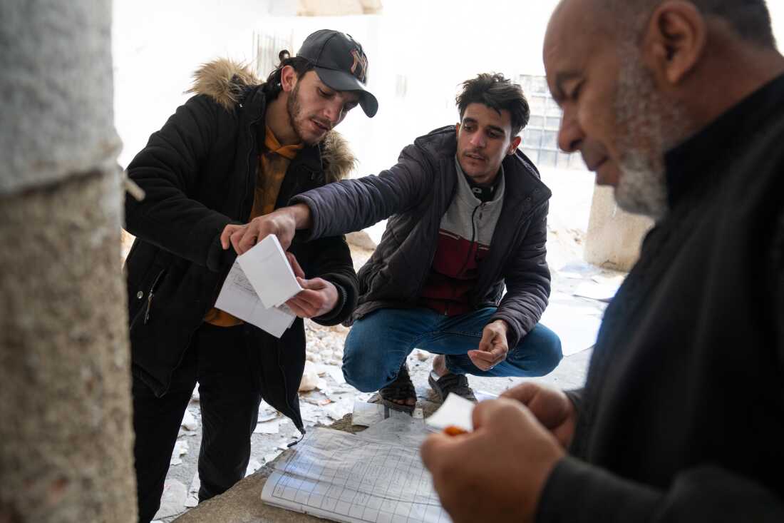 People search through handwritten notes and log books that are strewn around Sednaya prison just North of Damascus. Many are still looking for loved ones who were detained by the Assad regime.