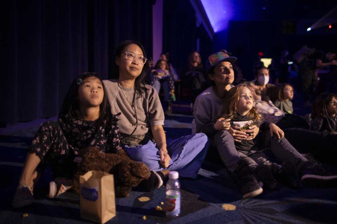 Iris Wong (left) sits with her mother Tina Yen and Tania Verafield holds her son Leo Bane as they watch the show.