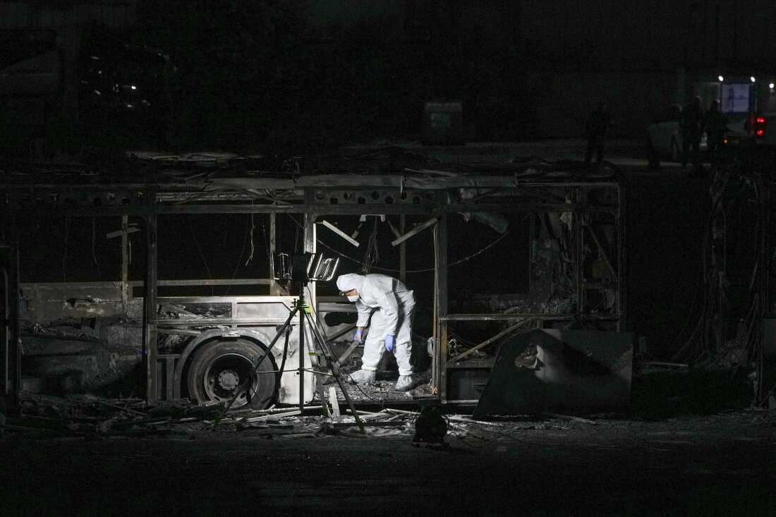 An Israeli police officer inspects the scene of one of a series of bus explosions in what authorities said appeared to be a militant attack in Bat Yam, central Israel on Feb. 20, 2025.