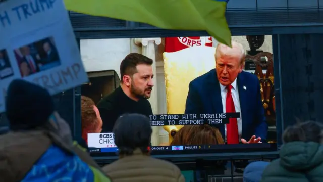 متظاهرون في مدينة شيكاغو يدعمون أوكرانيا أثناء متابعة الأخبار المحلية على شاشة خارجية كبيرة في 2 مارس/آذار 2025 في شيكاغو