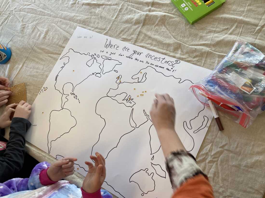 Children place gold stickers on a hand drawn map on a posterboard.