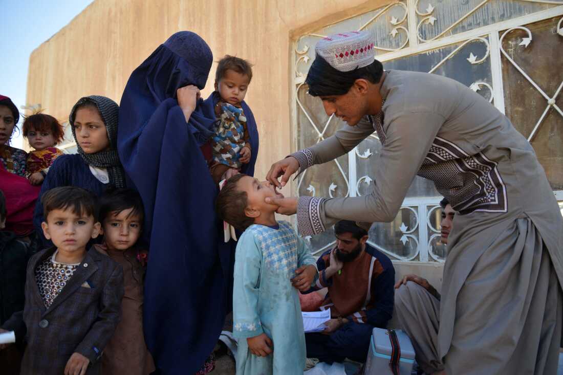 An Afghan health worker administers polio vaccine drops to a child during a polio vaccination campaign in Kandahar on December 23, 2024.