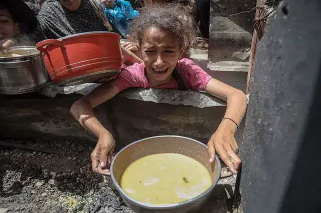 فتاة تحمل وعاءً للحصول على طعام في مخيم جباليا للاجئين، مدينة غزة، غزة في 19 مايو/أيار 2025. 