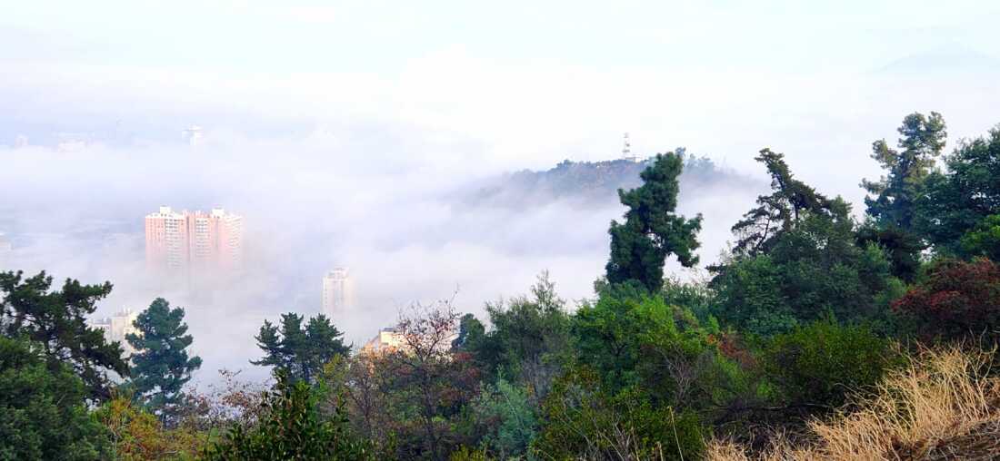 Morning fog shrouds Santiago's neighborhoods and hills during an autumn hike.