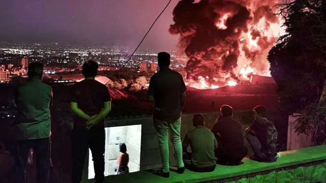 إيرانيون يرصدون دخاناً ونيراناً ناجمة عن هجوم إسرائيلي على مستودع نفط شهران في طهران، في 15 يونيو/حزيران 2025