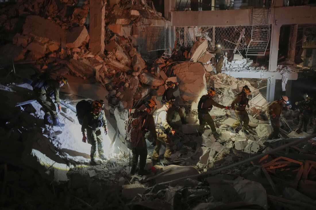 Israeli security forces inspect a destroyed building that was hit by a missile fired from Iran, near Tel Aviv, Israel, early Sunday, June 15, 2025. 