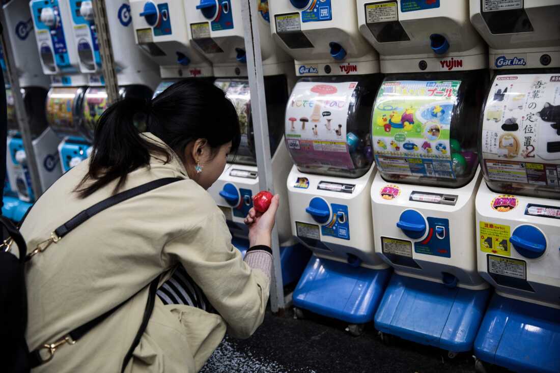 In this picture taken on Nov. 14, 2017, a woman looks at her newly-dispensed item in her hunt for capsule toys at a store in Tokyo's Akihabara district.