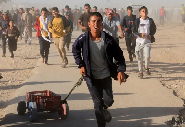صورة لفلسطيني يجر عربة صغيرة باتجاه موقع توزيع مساعدات في قطاع غزة.