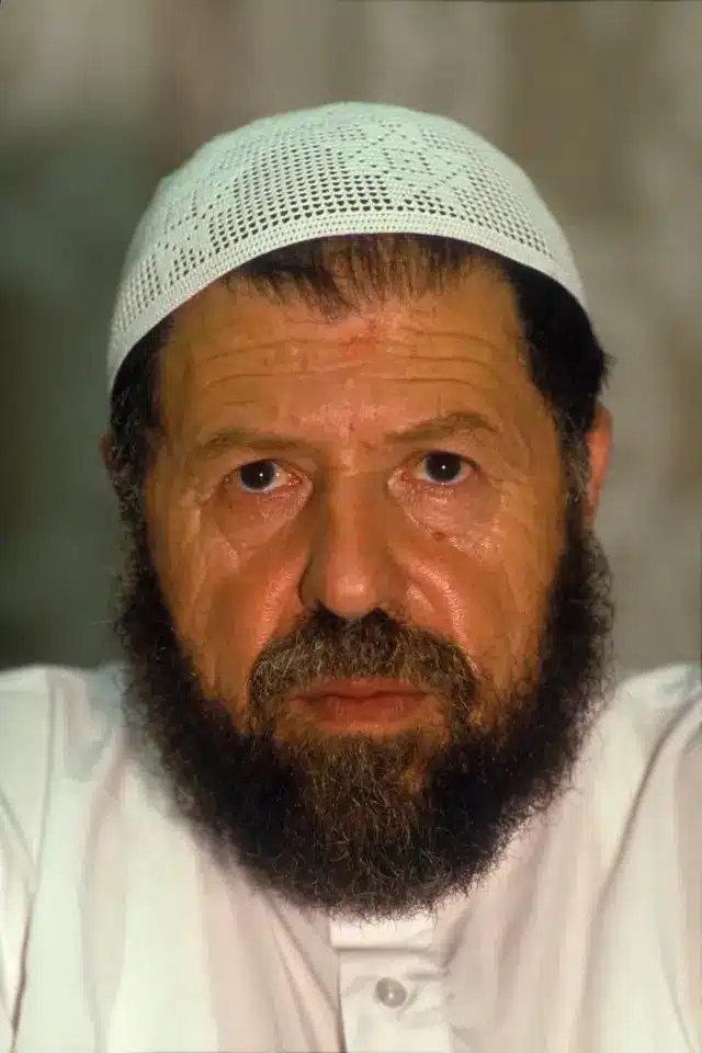 صورة لعباس مدني وهو ملتحٍ ويرتدي جلبابا أبيض وطاقية بيضاء.