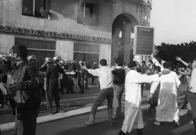  متظاهرون من الجبهة الإسلامية للإنقاذ الجزائرية يرددون شعارات نحو شرطة مكافحة الشغب خلال تظاهرة وسط الجزائر العاصمة في مايو/أيار 1991.