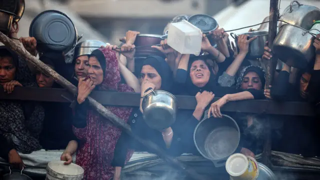فلسطينيون يتجمعون عند نقطة توزيع طعام في مدينة غزة، 20 يوليو/تموز 2025. أفاد برنامج الغذاء العالمي أن ما يقرب من ثلث سكان غزة لا يأكلون لأيام متواصلة، وأن "الآلاف" على "حافة جوع كارثي".