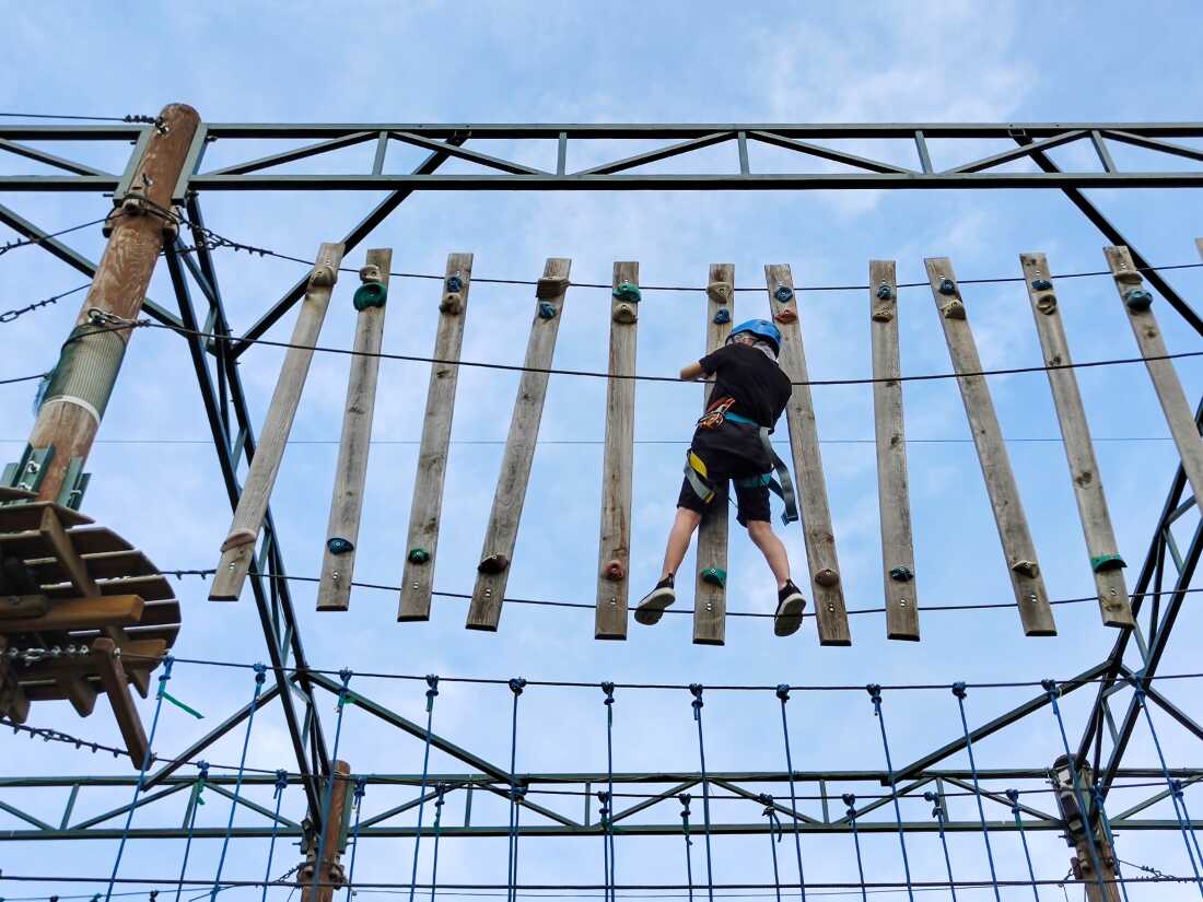 A kid climbing a suspension rope bridge