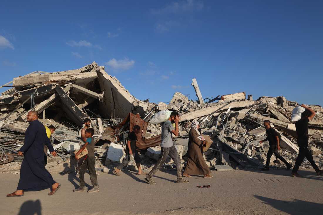 People, some carrying aid parcels, walk along the Salah al-Din road near the Nusseirat refugee camp in the central Gaza Strip, used by food-seeking Palestinians to reach an aid distribution point set up by the privately-run Gaza Humanitarian Foundation.