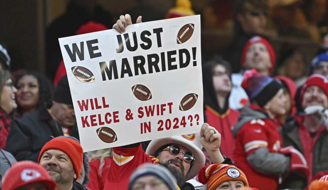 Fans hold up a sigh about Travis Kelce and Taylor Swift during a Kansas City Chiefs home game in December 2023, months into their relationship.