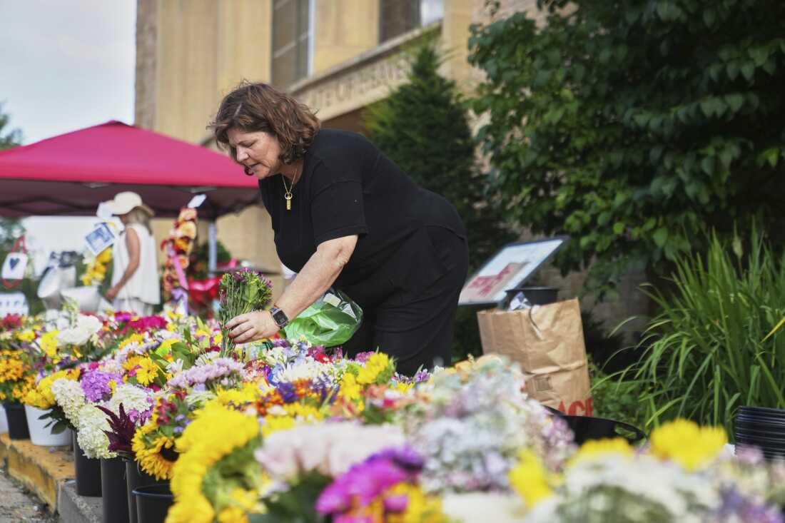 Annique London, a parent volunteer, helps with flowers at a memorial at Annunciation Catholic Church after Wednesday's school shooting, Thursday, Aug. 28, 2025, in Minneapolis. 