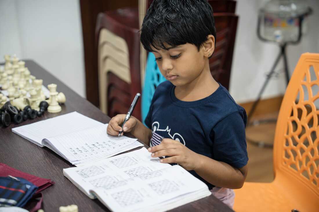 Six-year-old Sriharika, a beginner, studies chess theory while other students play matches following their classes at the Madras School of Chess in Chennai, India.