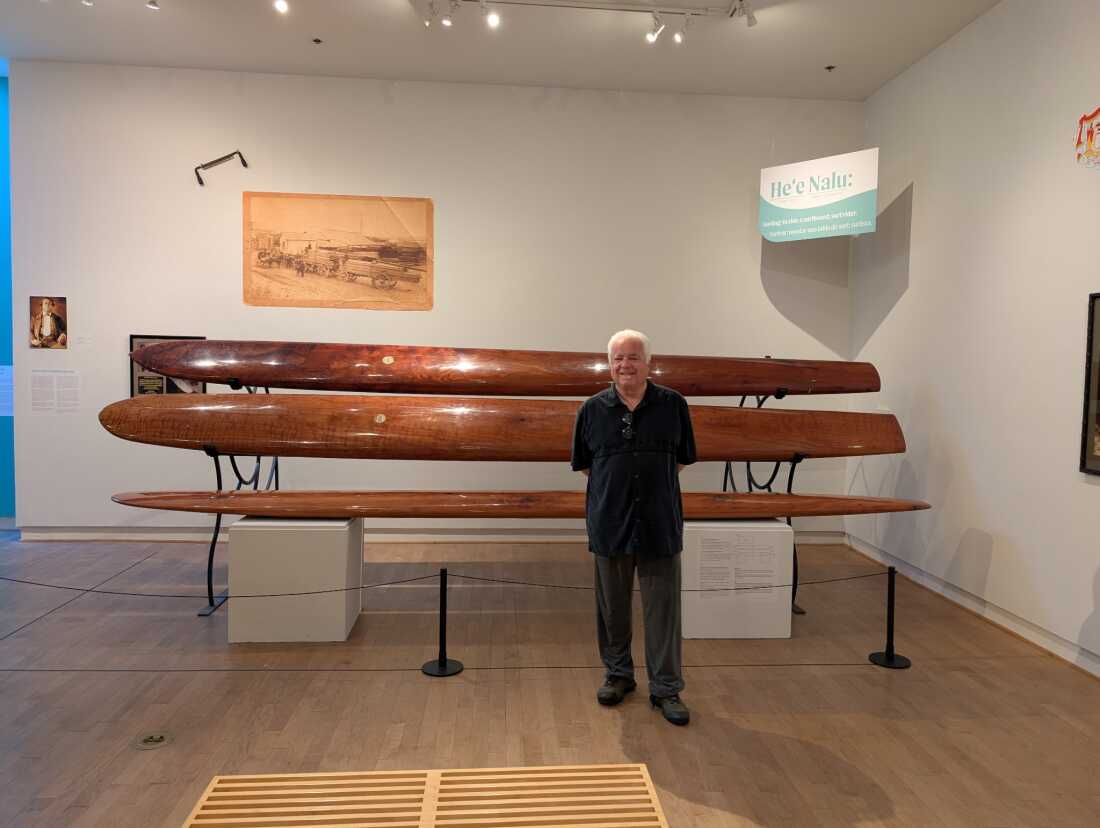 Cultural historian and surfer Geoffrey Dunn poses in front of modern reproductions of the redwood boards the Hawaiian princes built and used during the stay in Santa Cruz, Calif.