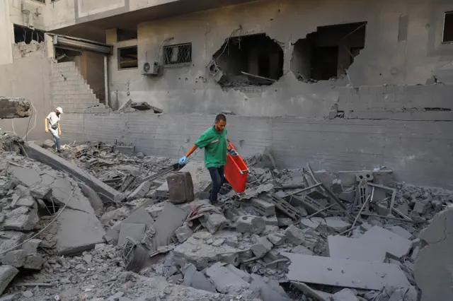 يحمل مسعف نقالة، بينما يتفقد فلسطينيون الدمار في حي سكني، في أعقاب عملية إسرائيلية في المنطقة، بعد أن وافقت حماس على إطلاق سراح الرهائن وقبول بعض الشروط الأخرى في خطة أمريكية لإنهاء الحرب، في مدينة غزة، 4 أكتوبر/تشرين الأول 2025