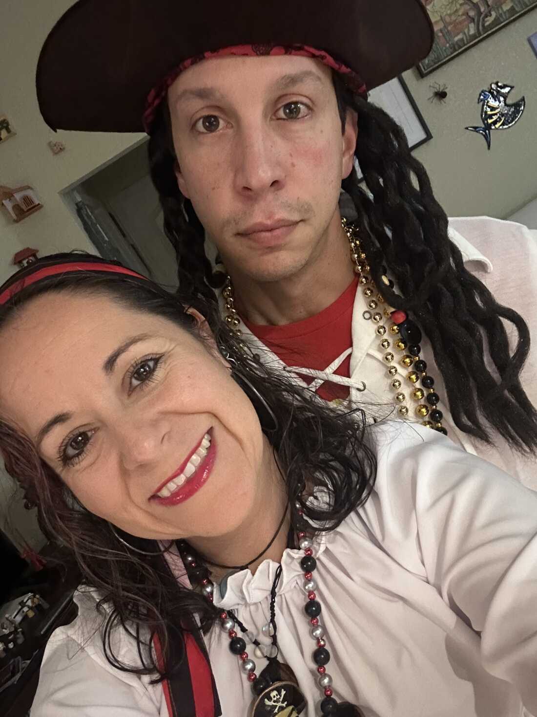 Stephanie Espinosa and Matthew Held, photographed from about the shoulders up, are dressed in pirate costumes. Both are wearing loose white tops. Held is wearing a pirate hat.
