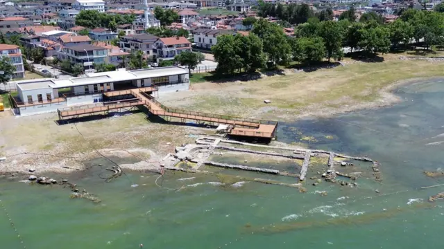 تُظهر صورة جوية لموقع الحفريات في إزنيق أعمالاً حجرية مغمورة جزئياً بالمياه ترسم حدود جدران كنيسة قديمة، فيما يمتد رصيف مراقبة فوق المياه انطلاقاً من مبنى مجاور.