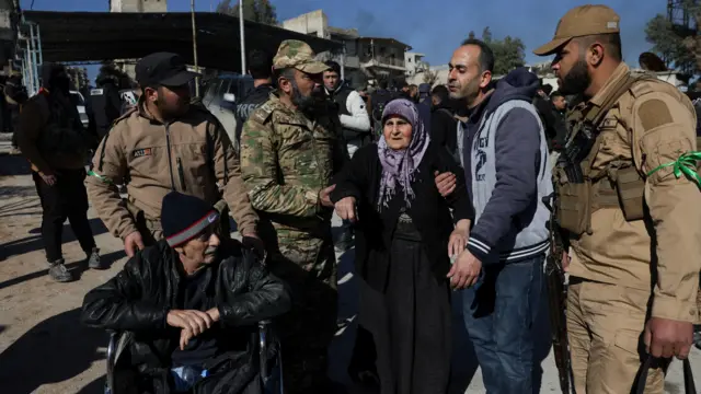 يتلقى السكان المساعدة أثناء إجلائهم من حي الشيخ مقصود في حلب، سوريا، في 10 يناير/كانون الثاني 2026، عقب انهيار الاتفاق بين الحكومة السورية وقوات سوريا الديمقراطية. 