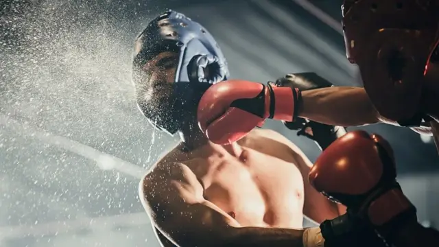 جانب من نزال ملاكمة إذ يضرب ملاكم لمنافسه الذي يخرج الماء من فمه 