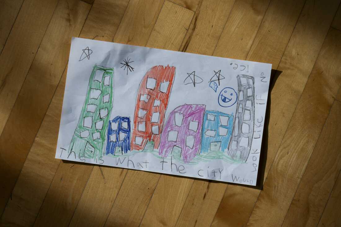 A child's drawing reads "This is what the city would look like if no ice." There are colorful tall and short buildings along with stars and a smiley face in the sky. 