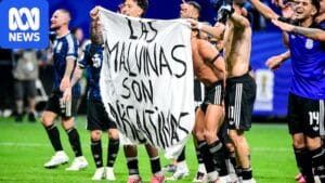 Argentina players holding a banner reading 'Las Malvinas son Argentinas' after World Cup semi-final win over England