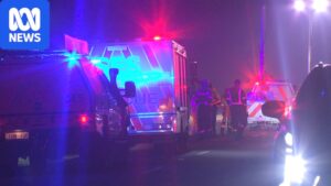 Emergency services at the Catani crash scene at night beside a car that left the road and flipped into a drainage culvert