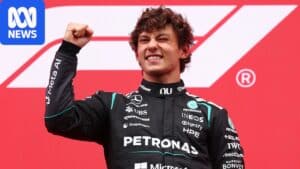 Kimi Antonelli on the podium after winning the Belgian Grand Prix at Spa, holding his helmet as the Italian anthem plays